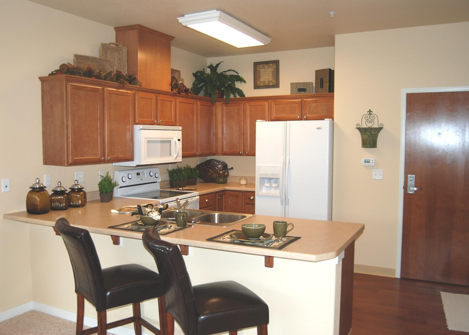 A living space with a patterned recliner and kitchen bar with three stools| Senior Apartment Homes 